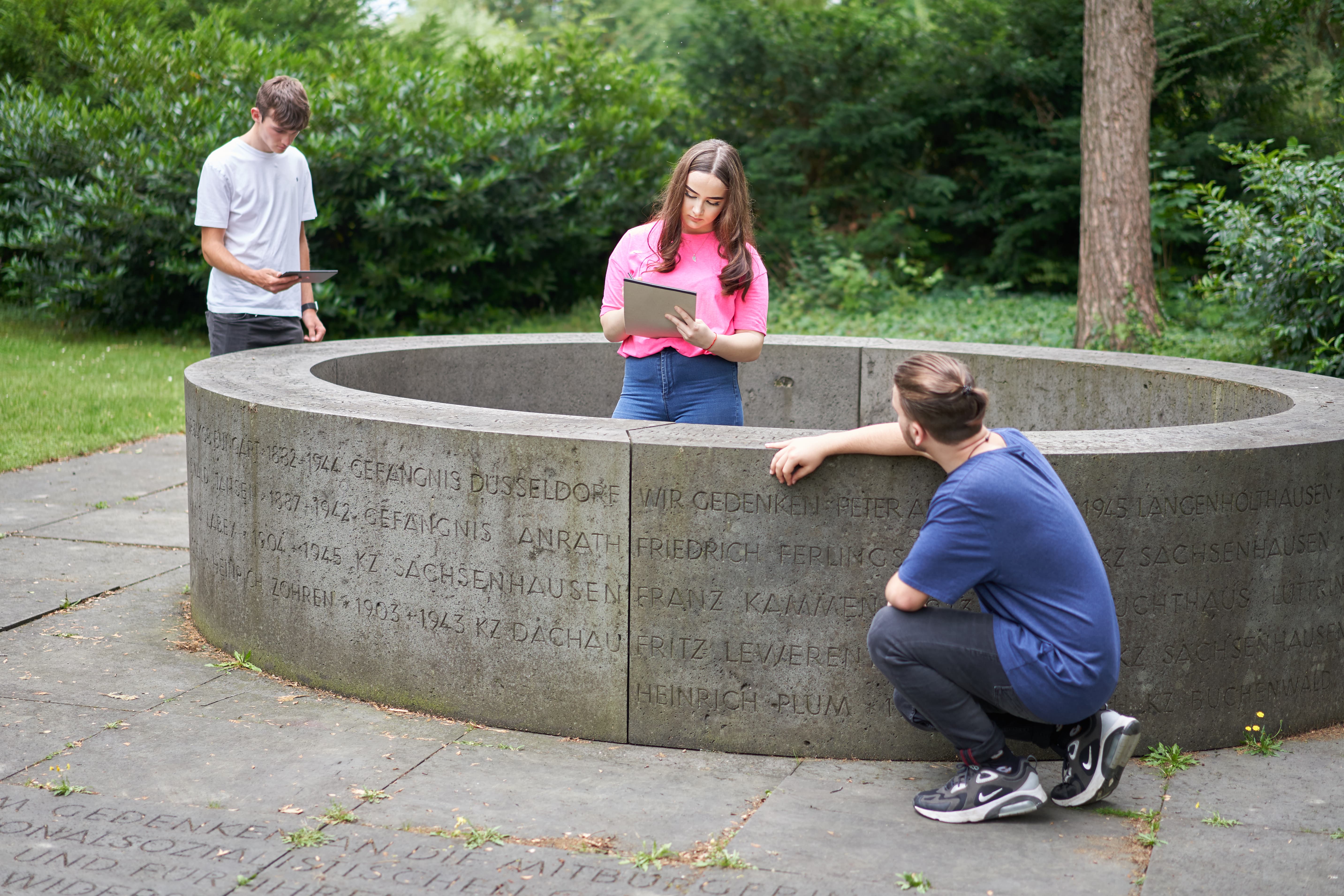 Drei Schüler*innen an einem Mahnmal im Rahmen einer Gedenkstättenfahrt