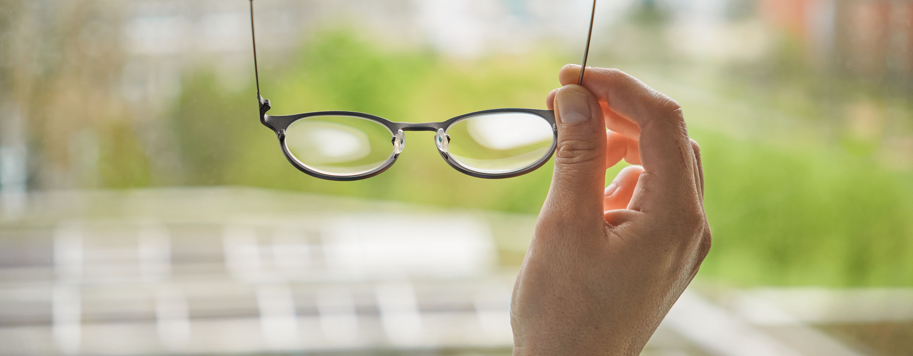 Bild zeigt Hand, die eine Brille hält