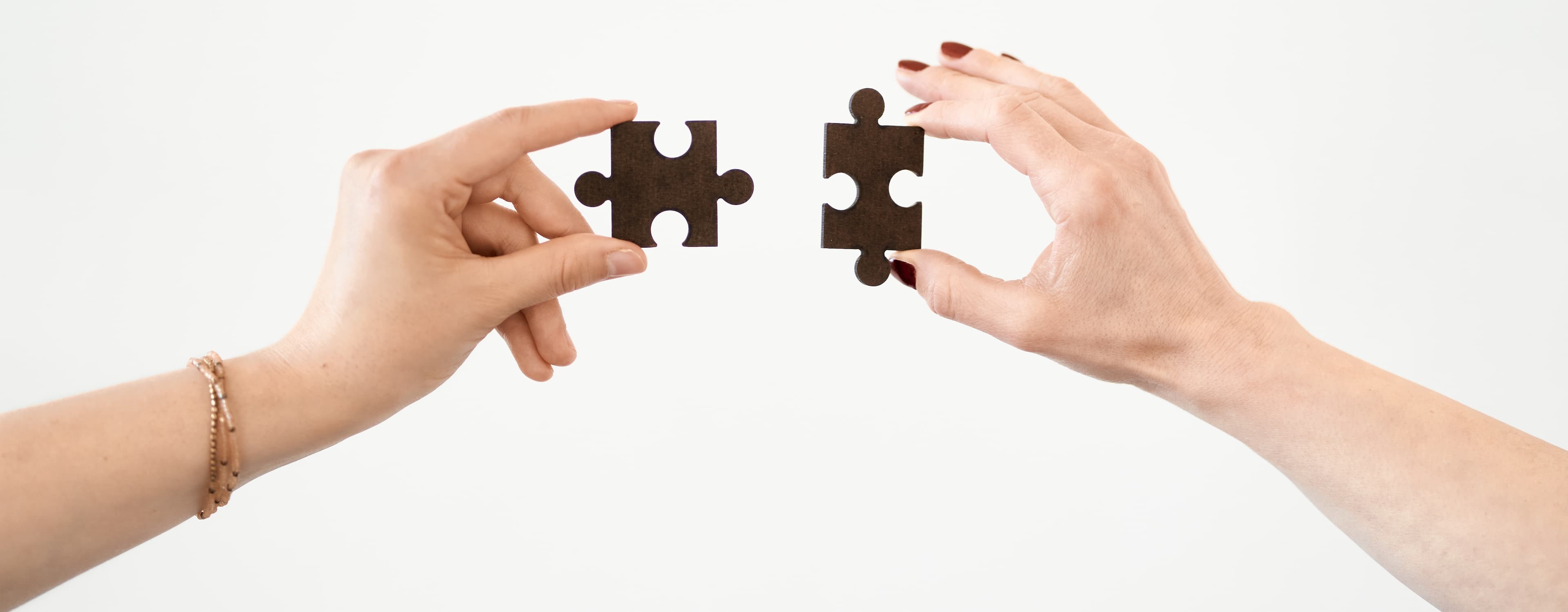 Bild zeigt Hände, die zwei Puzzleteile zusammensetzen